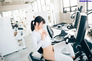 A woman is running on a treadmill in a gym.