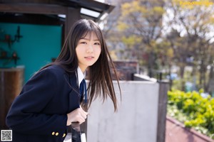 A woman in a school uniform standing on a bridge.