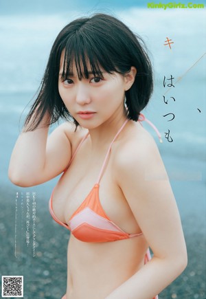 A woman in a black bikini sitting on a rock.