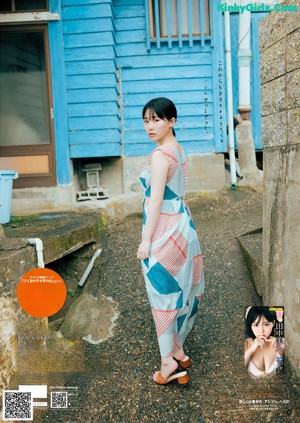 A woman leaning on a wooden bench in front of a building.