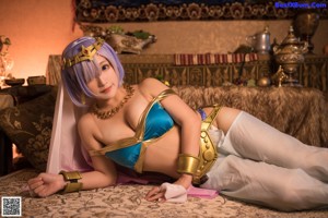 A woman in a blue and pink outfit sitting on a bed.
