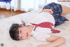 A woman in a white shirt and red tie laying on a bed.