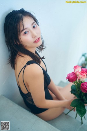 A woman laying on a table with a rose in her mouth.