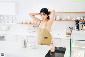 A woman sitting at a kitchen counter with a cup of coffee.