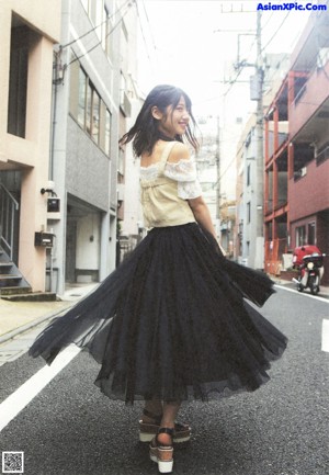 A woman in a white top and black skirt posing for a picture.