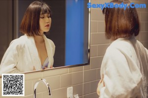 A woman in a bathrobe standing in a bathroom.