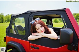 A woman in a bikini sitting in the back of a red car.