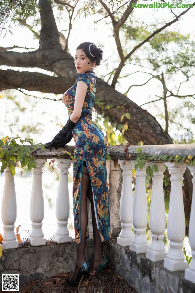 A woman in a blue dress standing on a railing.