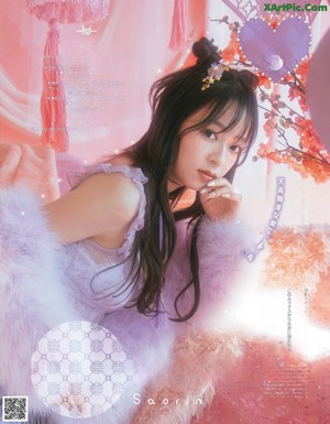 A woman in a white dress standing in front of a pink wall.