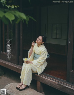 A woman in a kimono holding a sparkler in her hand.