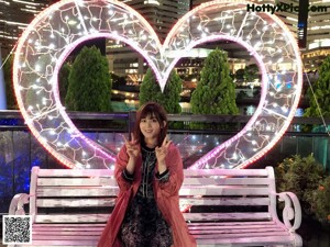 A young woman standing in the middle of a city at night.