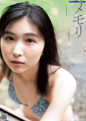 A woman in a blue swimsuit leaning against a wall.
