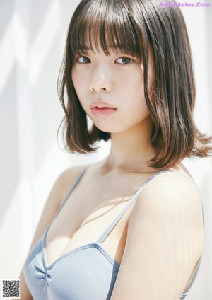 A woman in a white shirt and black bra top posing for a picture.