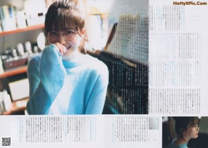 A young woman in a blue sweater smiles at the camera.