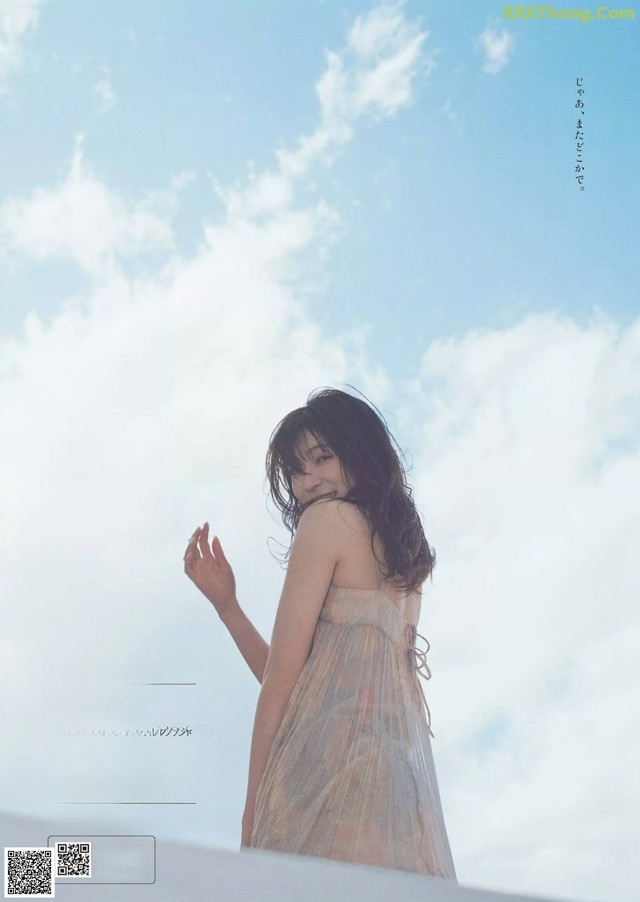 A woman in a dress standing on top of a hill.