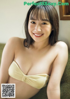 A woman in a yellow bikini laying on a green couch.