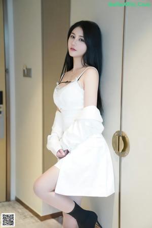 A woman in a white dress and black boots posing for a picture.