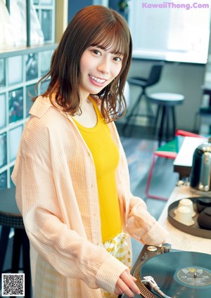 A woman in a green and white checkered shirt sitting on a red chair.
