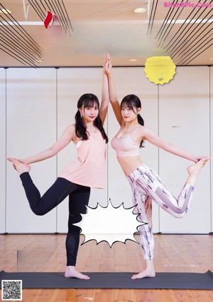 A couple of women doing yoga on a wooden floor.