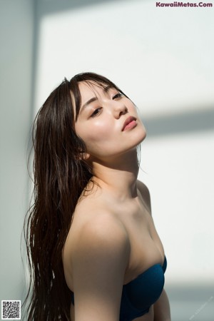 A woman in a black bikini sitting on the floor.