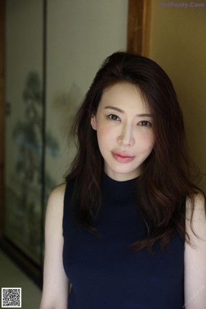 A woman with her back to the camera with her hand on her neck.