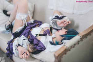 A woman in a maid outfit sitting on a chair.