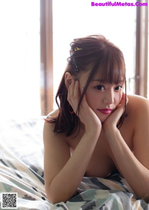 A woman in a pink shirt and blue panties posing on a table.